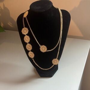 Long gold necklace with round ornaments.